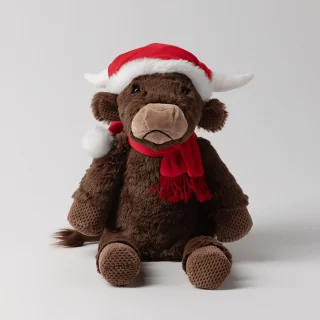 Brown plush highland cow with floppy ears wearing a red Santa hat and fringed scarf, the Jolly Ol' Saint Moo Scentsy Buddy