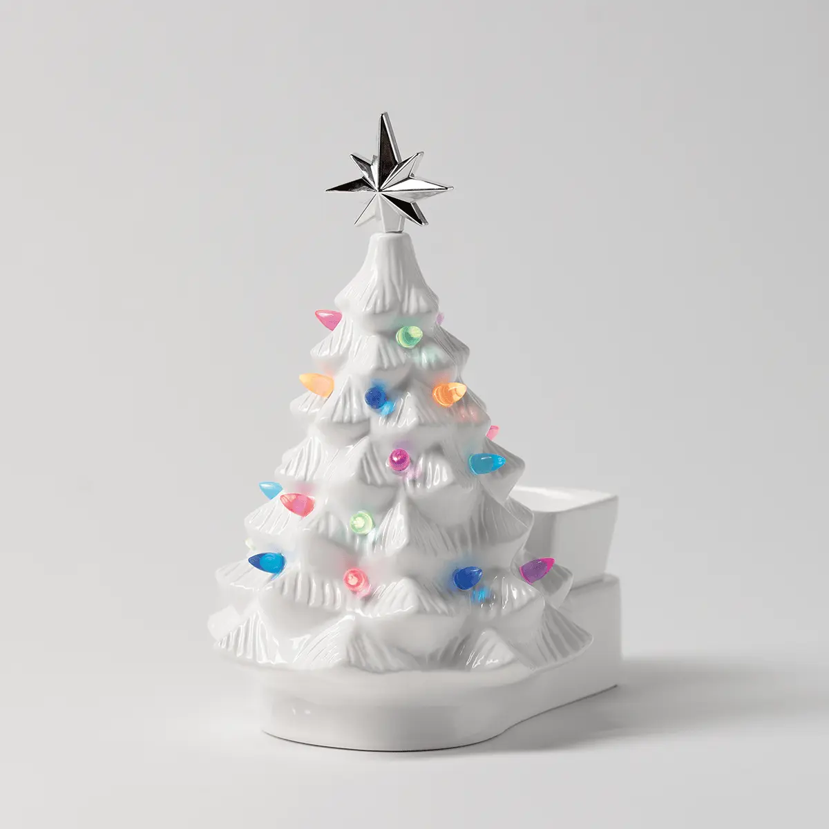 White ceramic Christmas tree warmer with textured branches, colourful gemstone ornaments, a silver star topper, and a round base