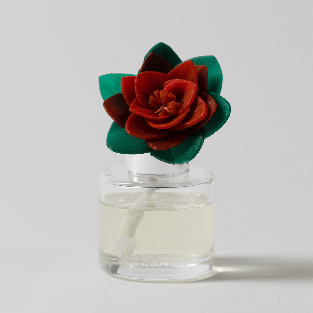 Red velvet rose with teal leaves in a clear glass bottle filled with pale liquid, the Mistletoe Mint - Radiant Red Poinsettia Fragrance Flower