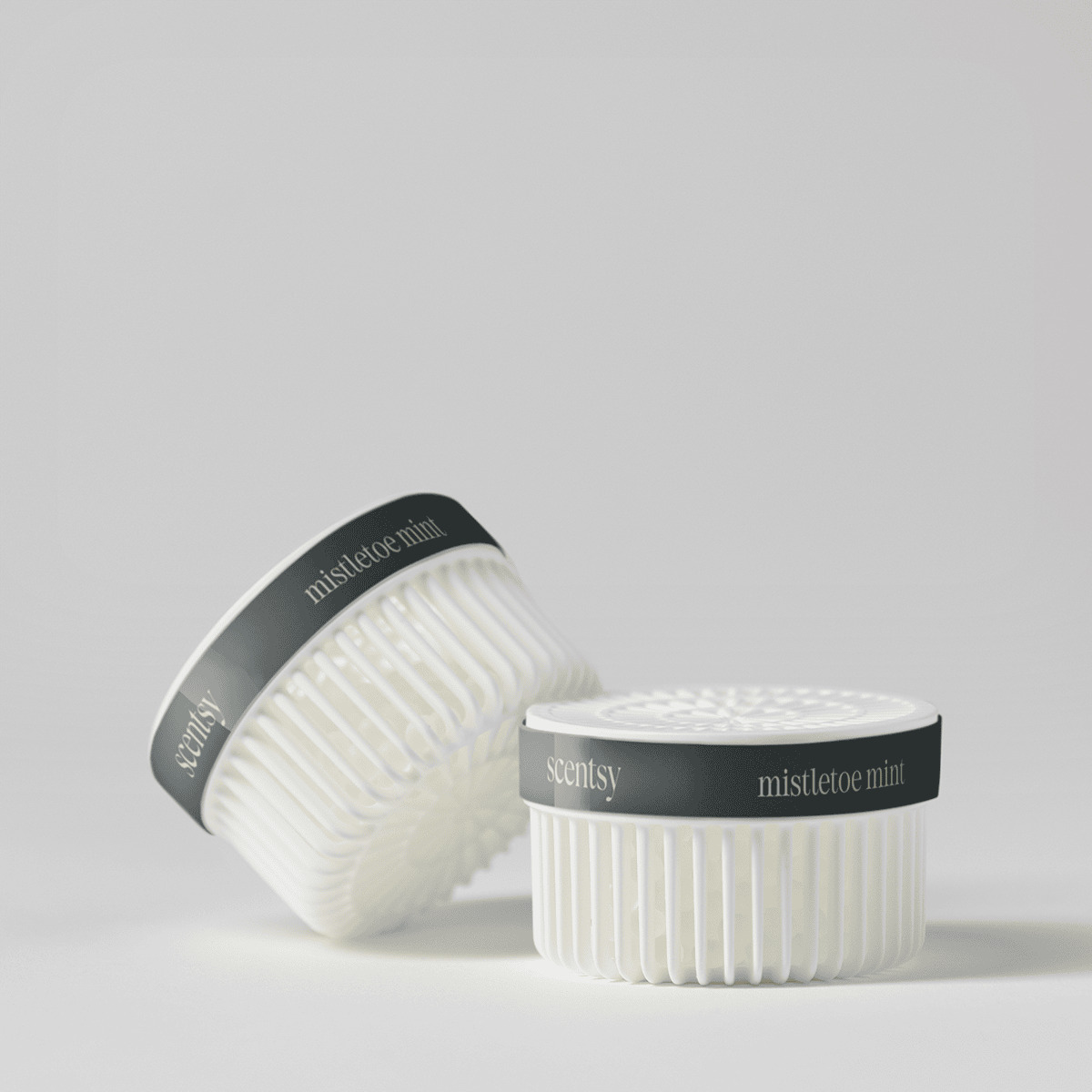 Two white ribbed pods with charcoal-grey lids stamped "mistletoe mint" and the Scentsy logo, displayed upright and tilted