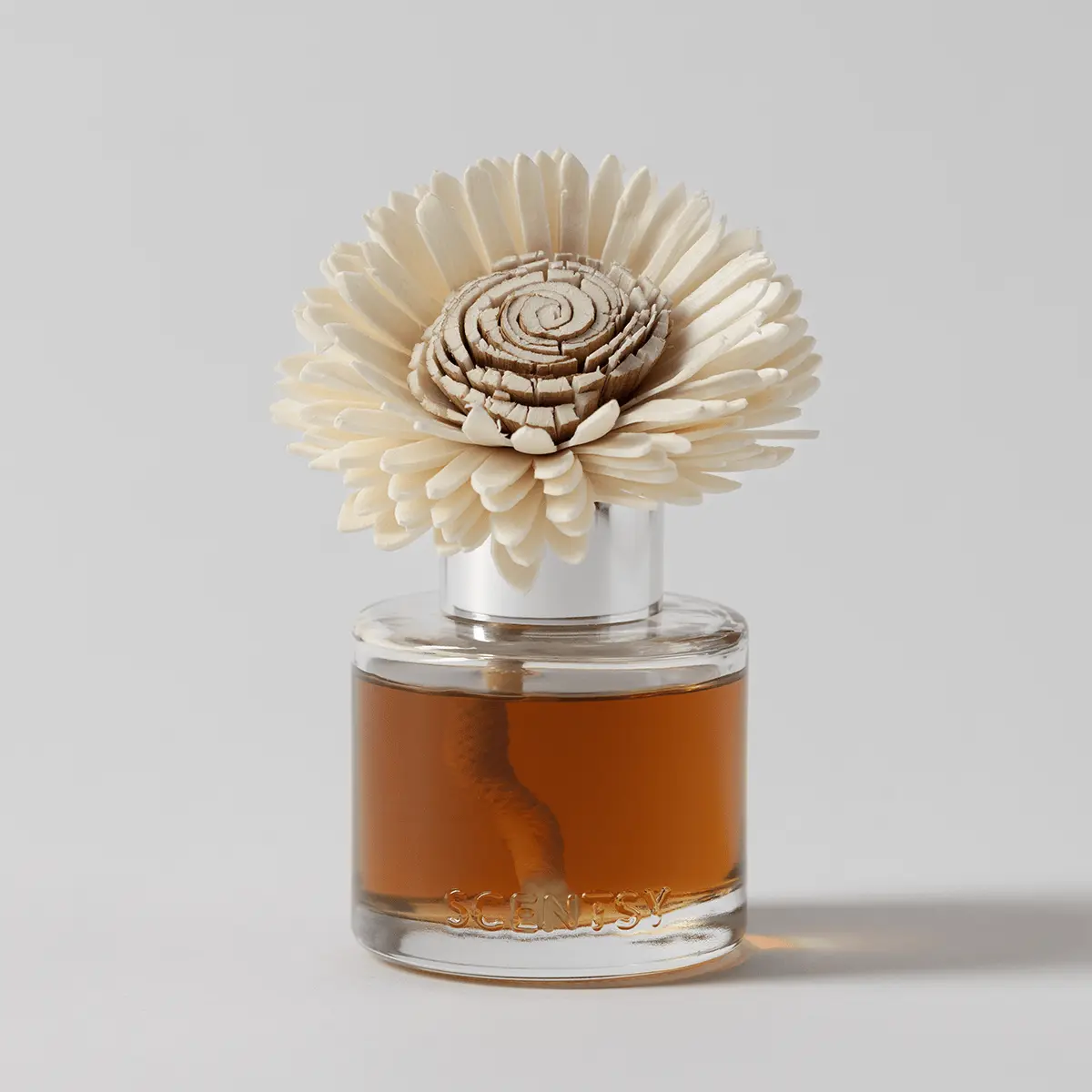Cream sculptural sunflower with layered petals and spiral centre in a glass bottle filled with amber liquid, the Sandalwood & Vanilla Pumpkin Fragrance Flower