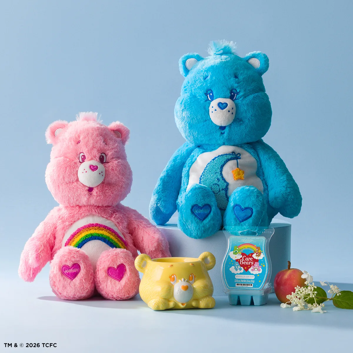 Care Bears Collection featuring a pink bear with rainbow chest design, turquoise bear with heart and star symbols, yellow bear head planter, Scentsy wax melt package, and decorative flowers against a pale blue background.