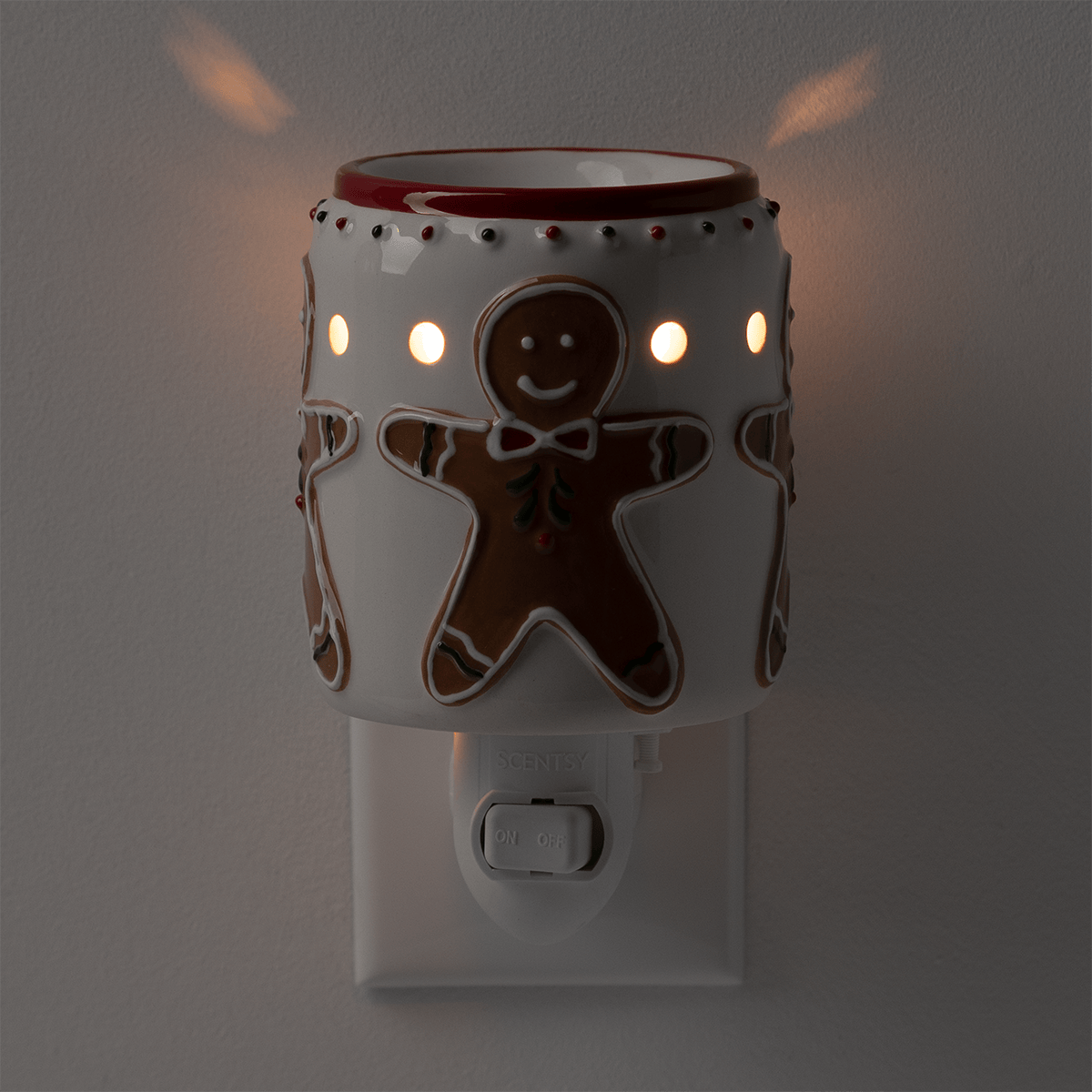 Cream-coloured mini warmer with gingerbread man design, cut-out details, and red trim, five illuminated circular vents, mounted on a white wall plug base