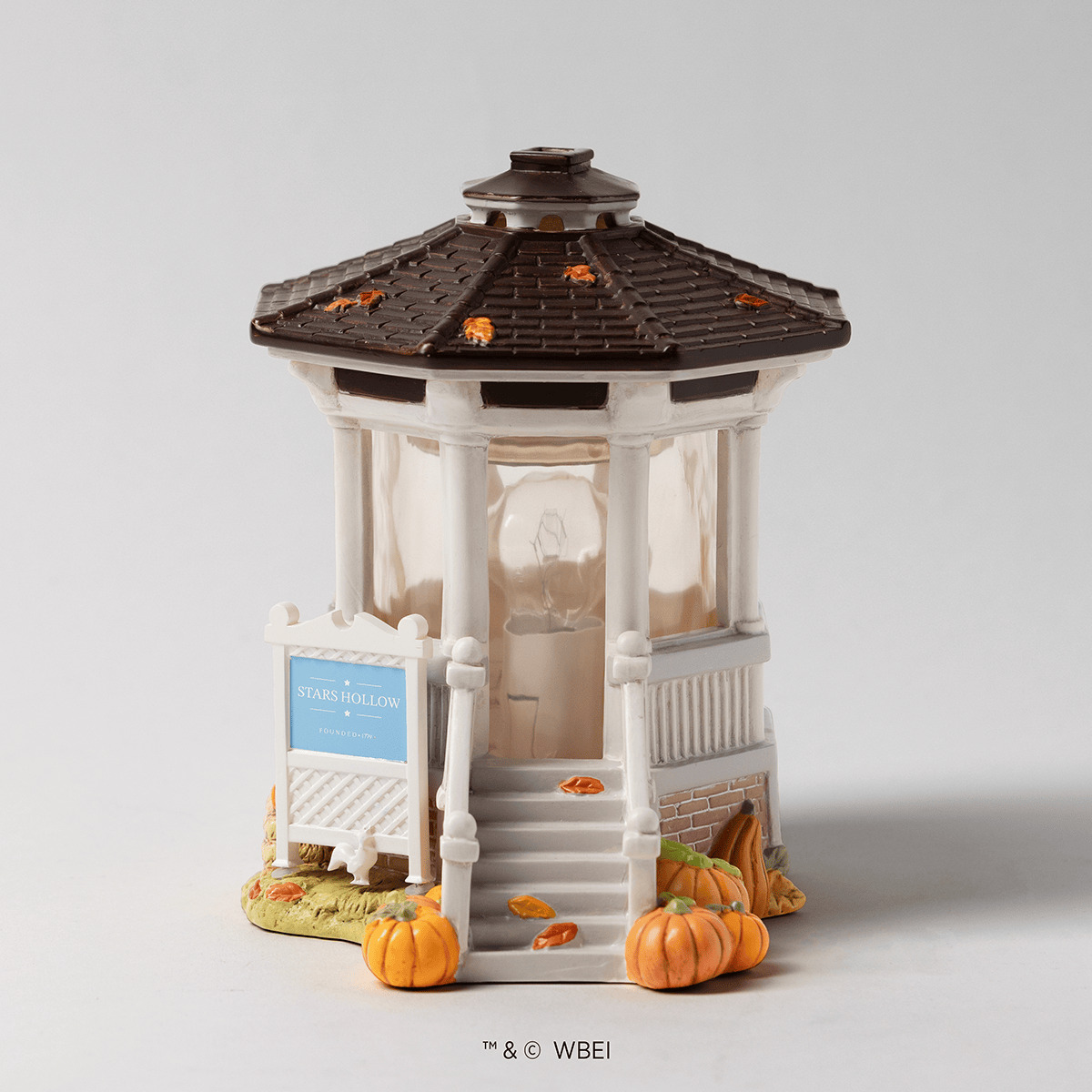 Cream and white gazebo-shaped warmer with a dark brown roof, featuring autumn leaf details, a blue "Stars Hollow" sign, and orange pumpkins at the base