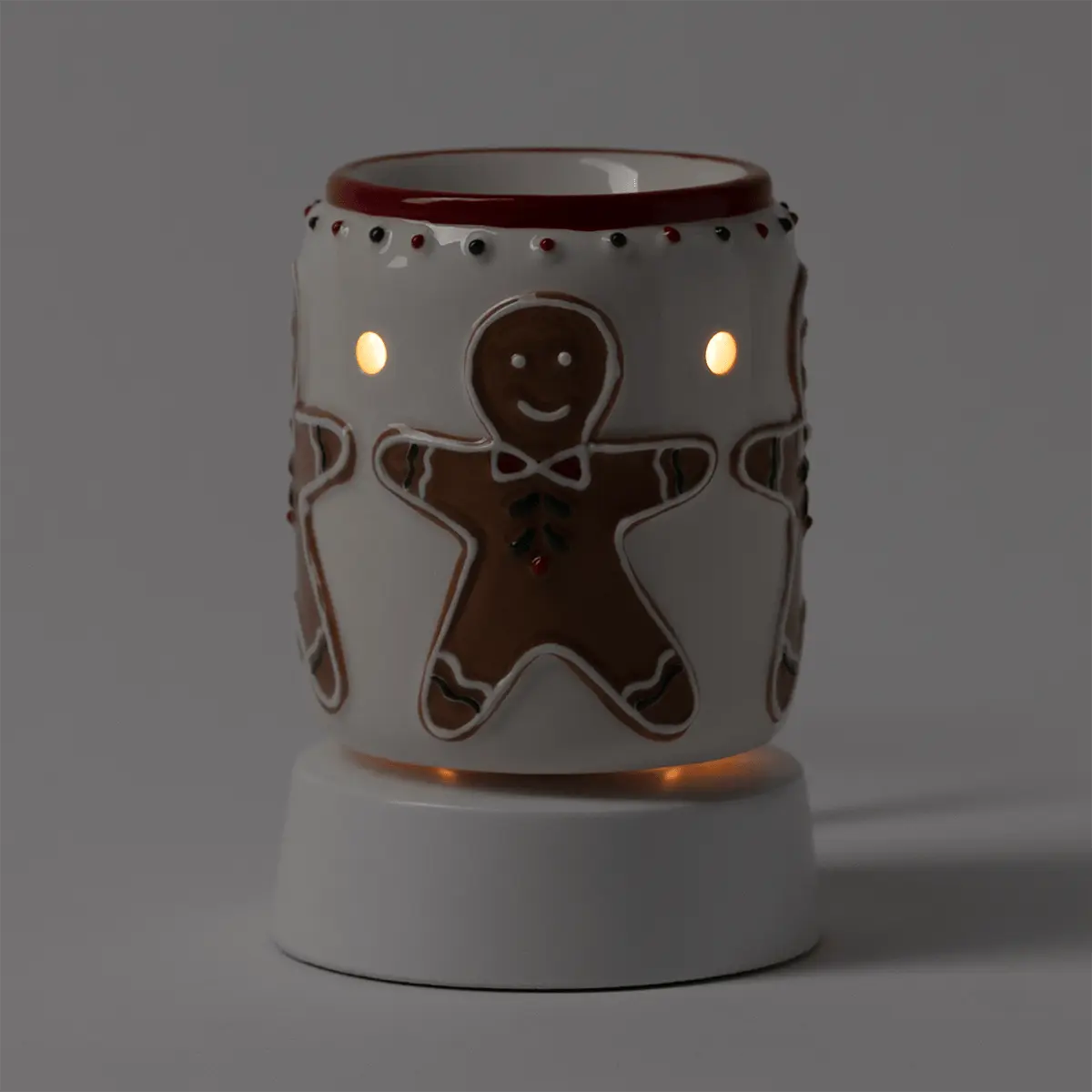 Cream ceramic mini warmer with gingerbread man cutout design, lit side vents, burgundy trim, and matching tabletop base, the Gingerbread Snap Mini Scentsy Warmer