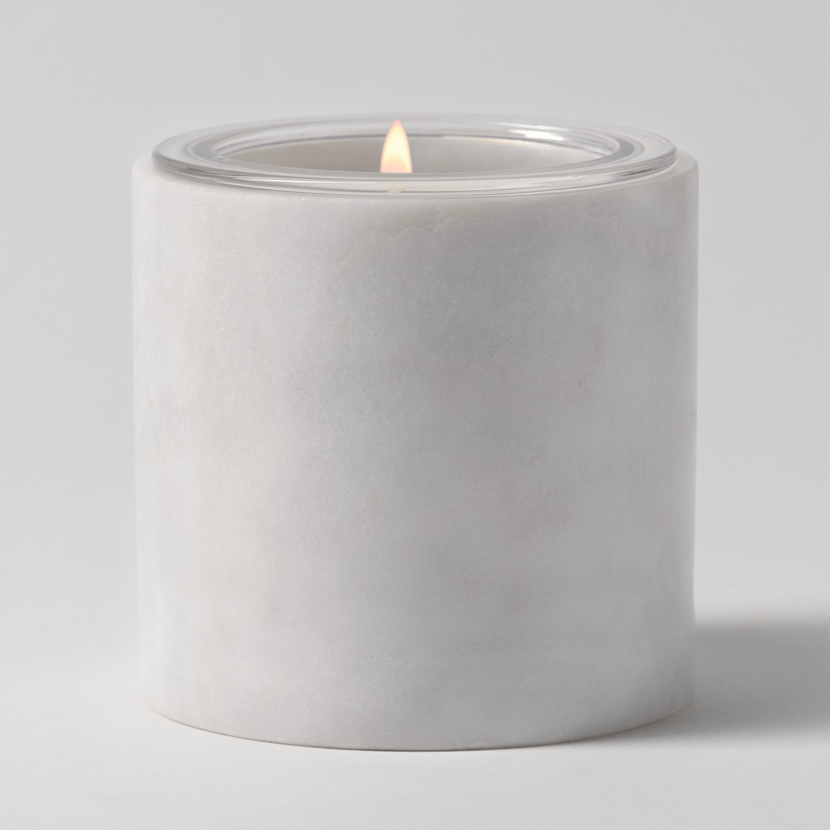 Solid white marble cylinder candle holder with soft natural veining, holding a clear glass Scentsy Candle Insert filled with cream wax
