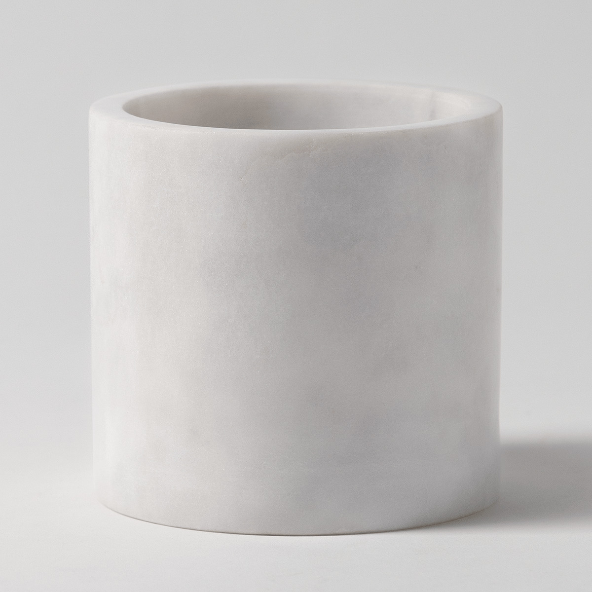 Solid white marble cylindrical candle holder with soft natural veining and a wide opening