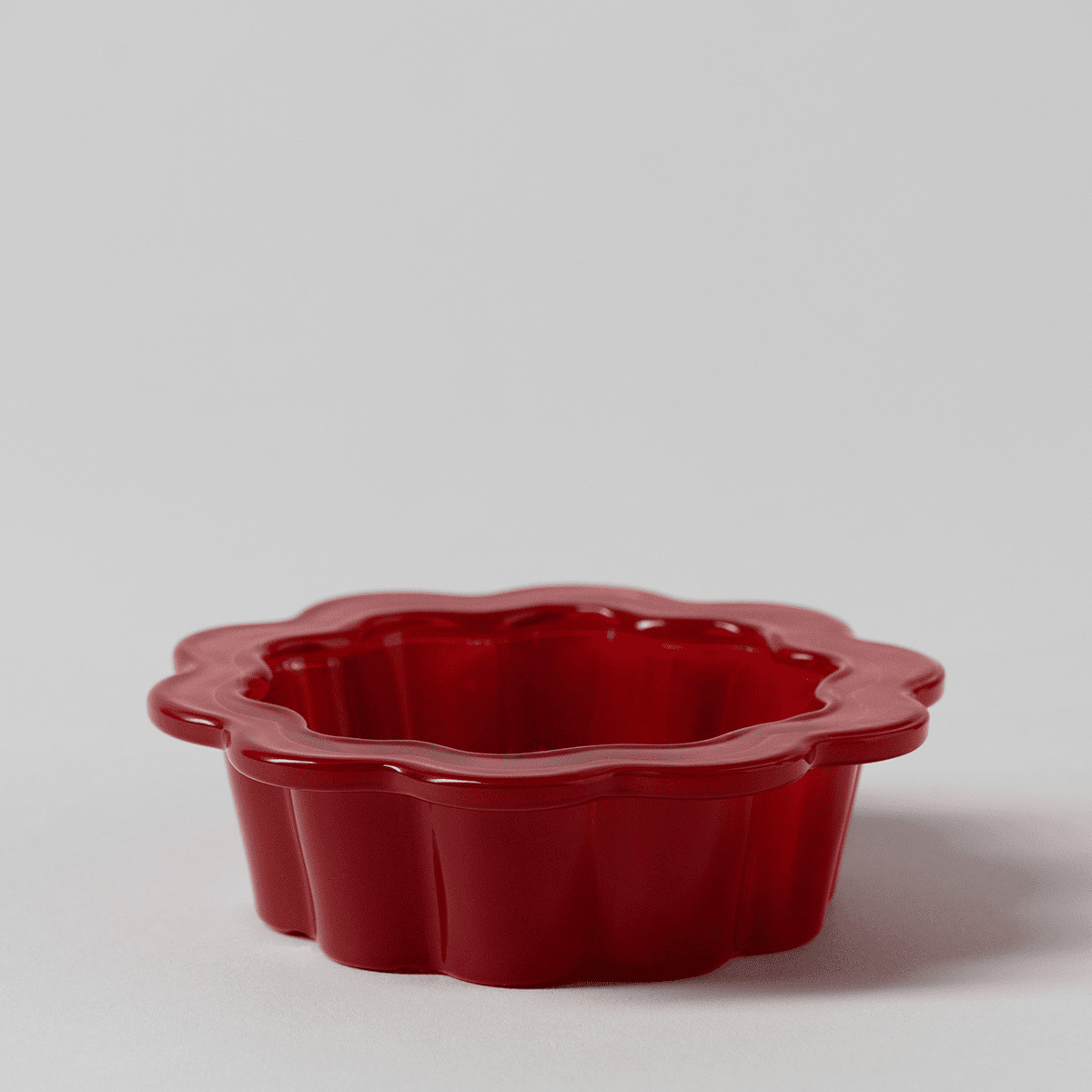 Glossy red ceramic dish with a scalloped, flower-shaped rim and fluted sides, the Petal Red Replacement Dish for a Scentsy Warmer