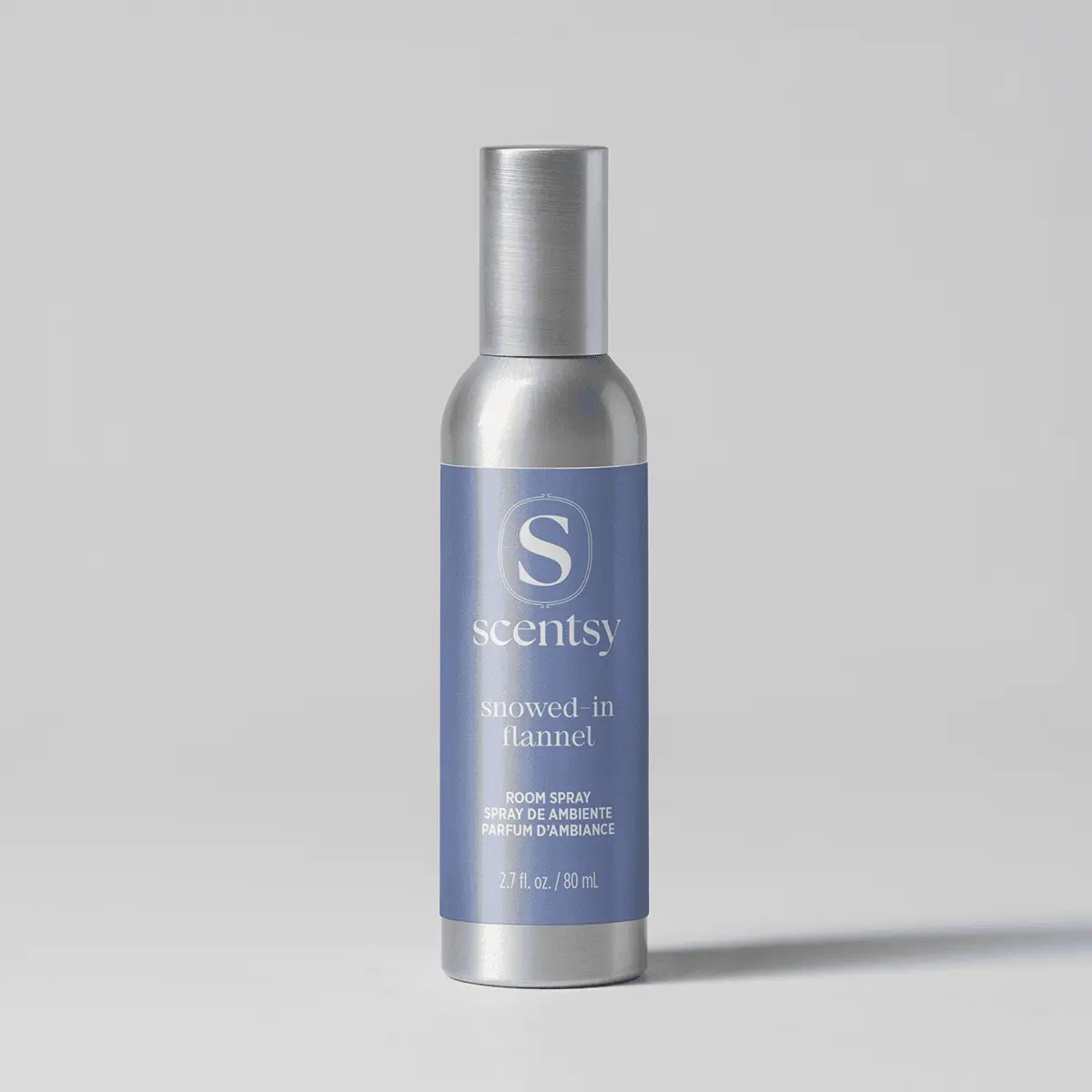 Metallic silver cylindrical room spray bottle with a blue label featuring the Scentsy logo and "Snowed-In Flannel Room Spray" text, 2.7 fl oz / 80 mL size