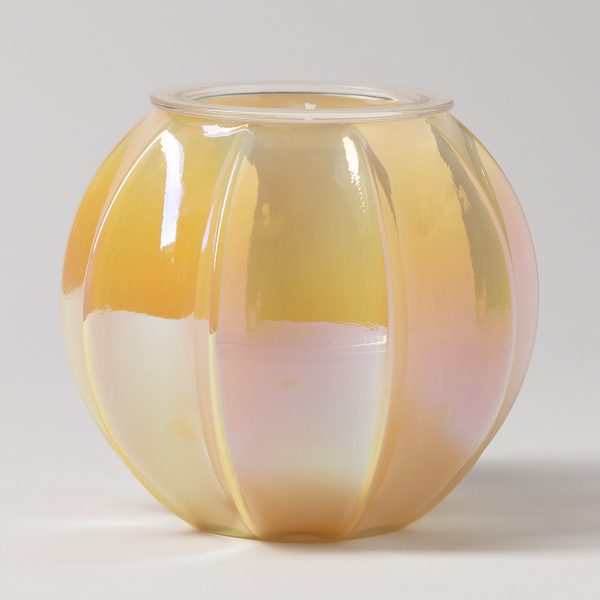 Rounded glass candle holder with vertical ribbed panels in an iridescent finish shading from golden peach to soft pink, the Sunset Light Candle Holder, containing a cream wax Scentsy Candle Insert