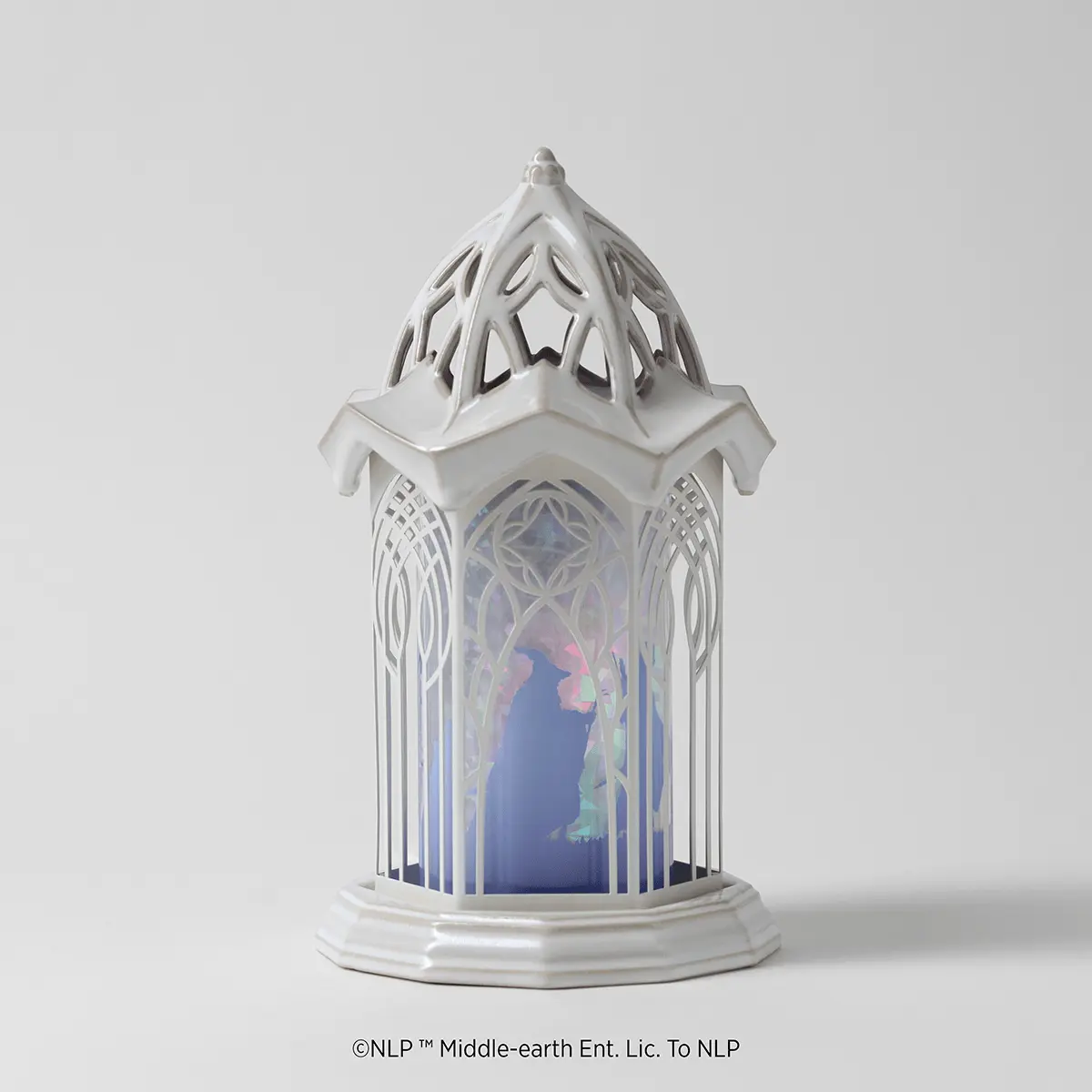 White ceramic warmer with an ornate gothic-inspired tower design, featuring pierced geometric patterns and a glowing interior scene of an elven figure in a blue-lit landscape, the Lord Of The Rings: Rivendell Scentsy Warmer