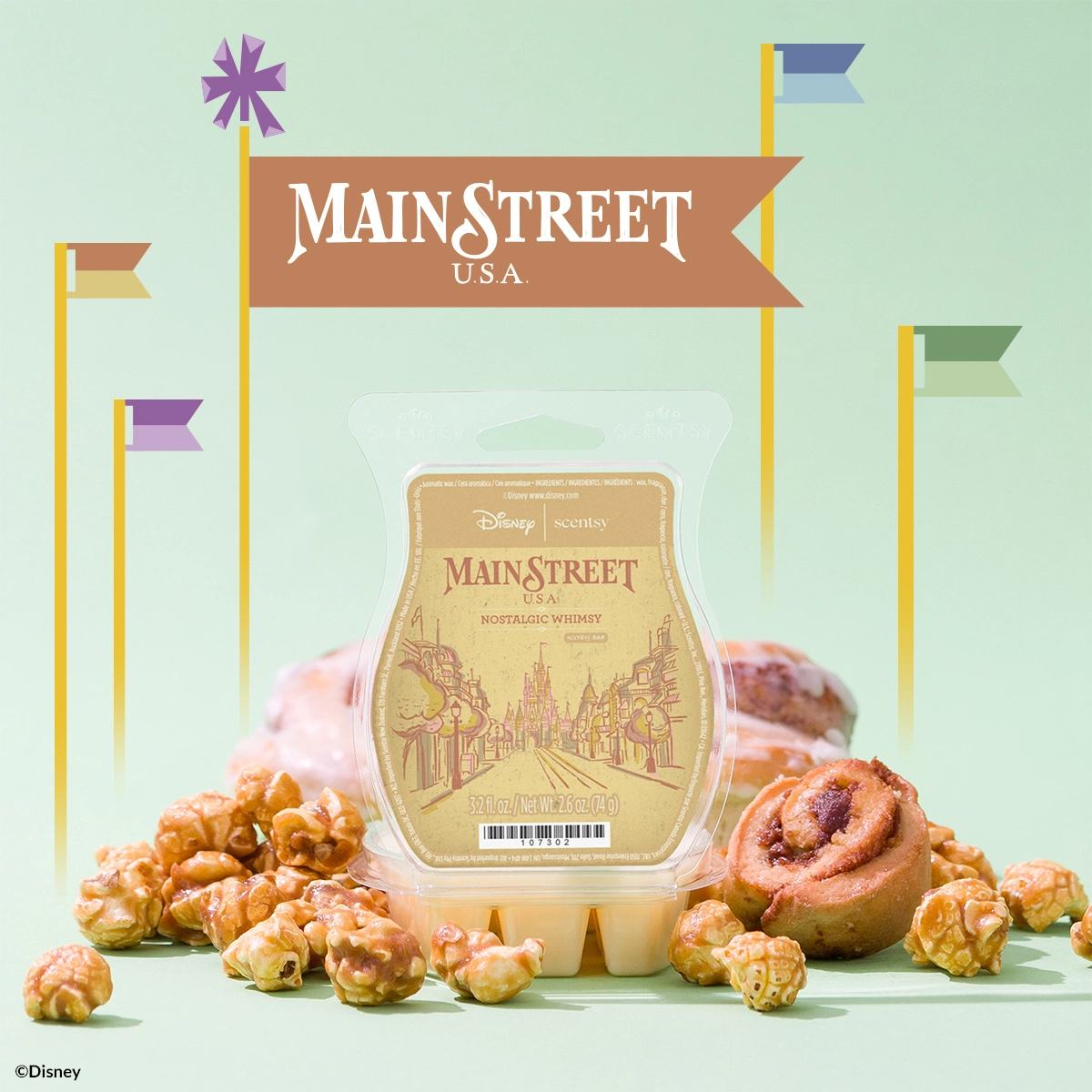 Scentsy wax bar with a cream-coloured label featuring Main Street U.S.A. imagery, surrounded by decorative pastries and a whimsical backdrop with coloured flags and a purple starburst, Walt Disney World - Scentsy Wax Collection