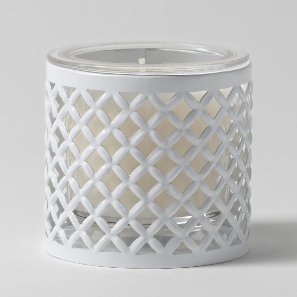 White cylindrical metal candle holder with an open lattice trellis cut-out pattern, containing a clear glass insert filled with cream wax, the White Trellis Candle Holder