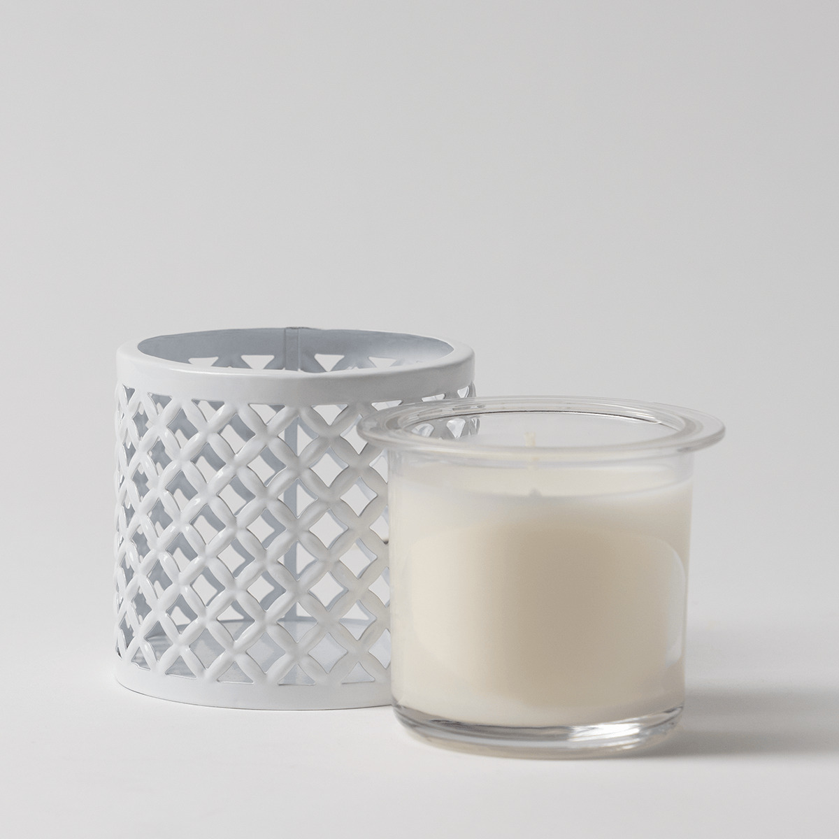 White metal candle holder with open lattice trellis pattern, shown with a clear glass Scentsy Candle Insert filled with cream wax