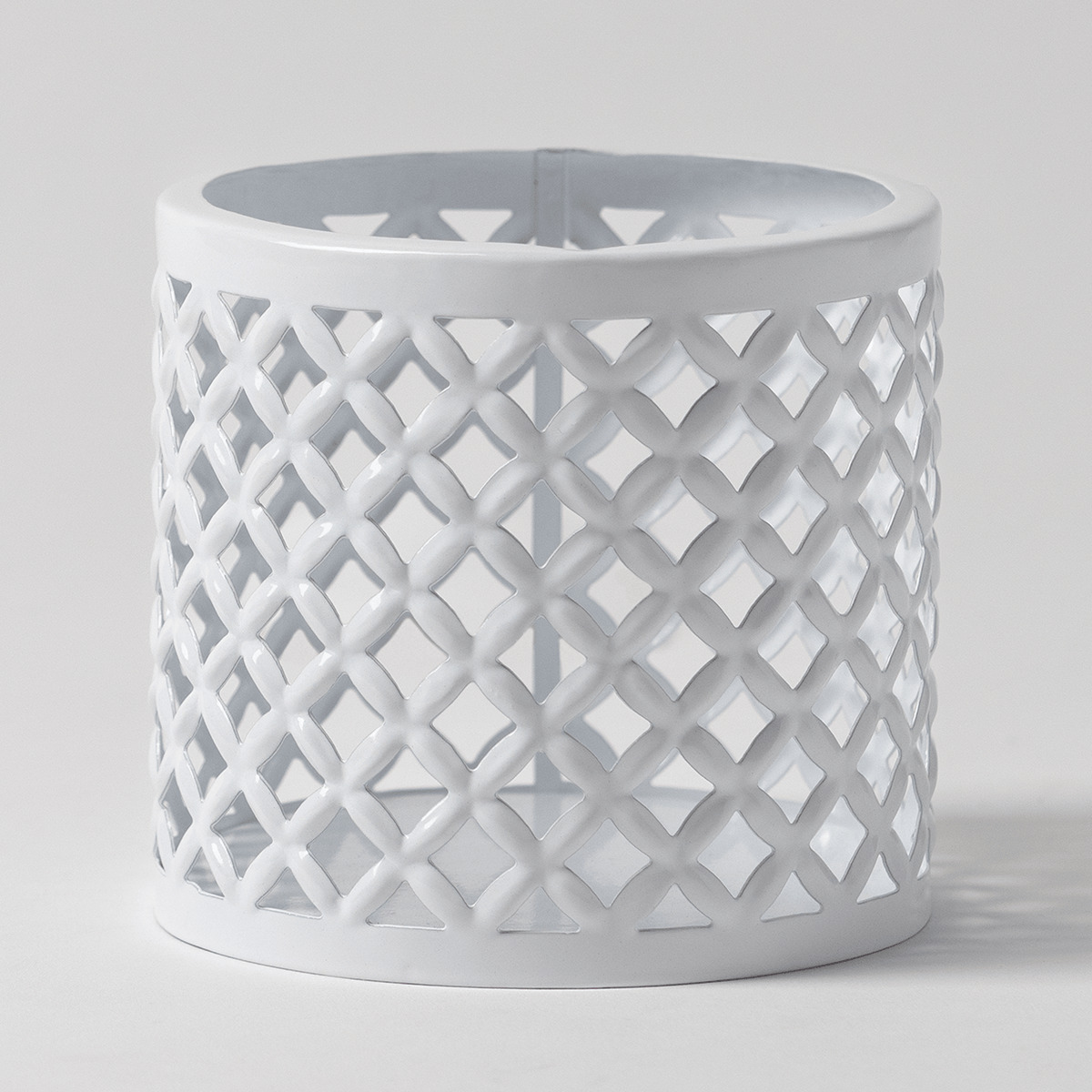 White metal candle holder with an open lattice trellis pattern and cylindrical form