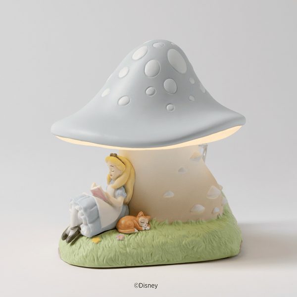 Pale blue spotted ceramic mushroom warmer glowing above Alice reading beside a sleeping kitten on grass, the Disney Alice in Wonderland: Down the Rabbit Hole Scentsy Warmer
