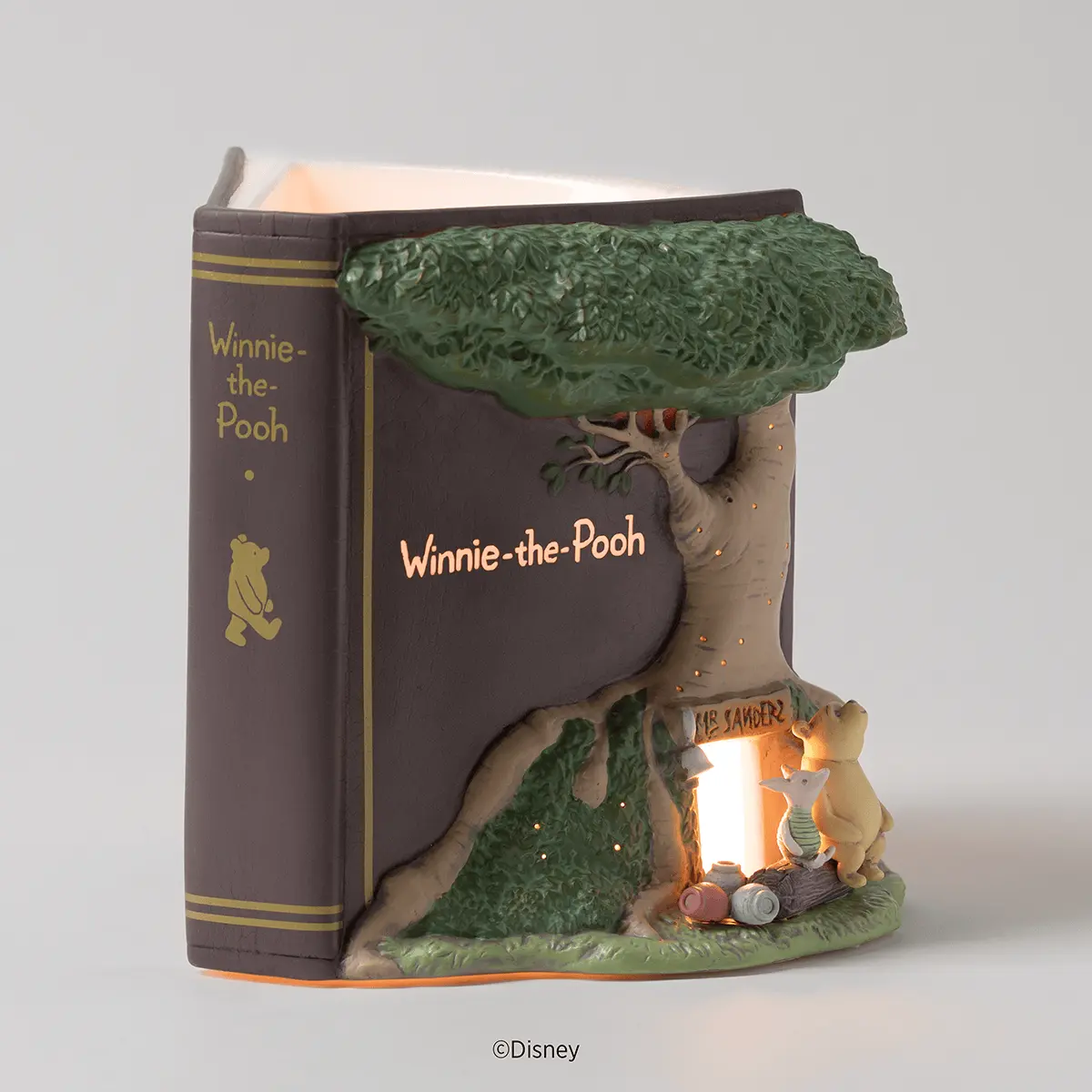 Brown storybook-shaped warmer with a sculpted tree, Pooh and Piglet by a glowing doorway, the Disney Winnie the Pooh: 100 Years of Friendship Scentsy Warmer