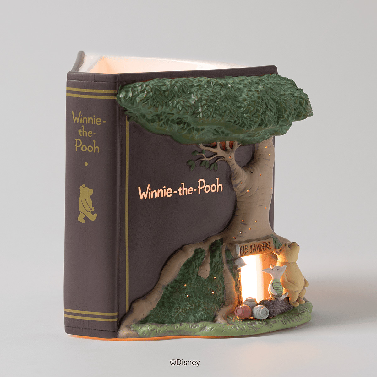 Ceramic warmer shaped like a brown Winnie-the-Pooh storybook, with Pooh and Piglet beneath a glowing sculpted tree