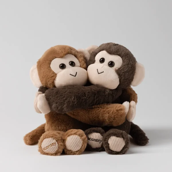 Two plush monkeys in light and dark brown fur hugging with cream faces and corduroy paw pads embroidered with scentsy, the Mango & Mochi Scentsy Hugging Buddies