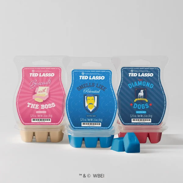 Three wax bar clamshells in pink, blue and navy with cream, blue and red wax and two loose blue cubes, the Ted Lasso - Scentsy Wax Collection